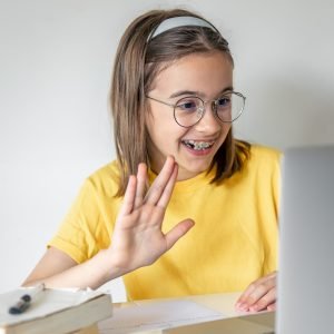 Smiling caucasian girl having video call in remote classroom, using laptop.